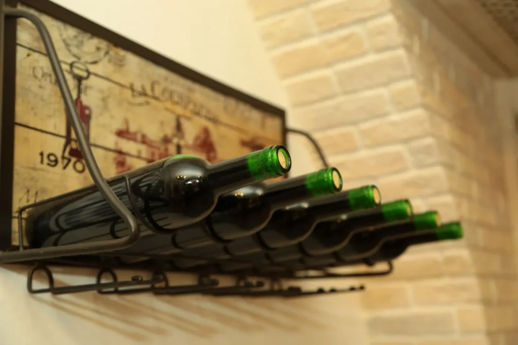 Wine bottles neatly arranged on a rack against a rustic wall, in a cozy home.