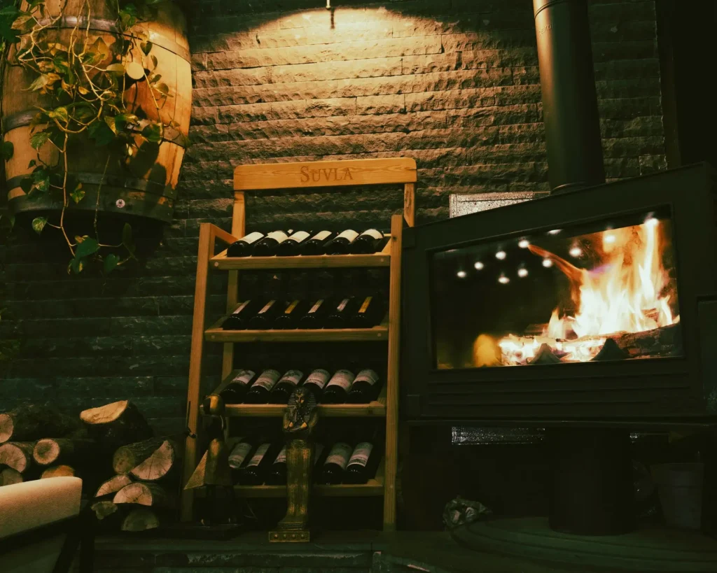 Wine rack positioned beside a fireplace, exposing stored wine to heat.